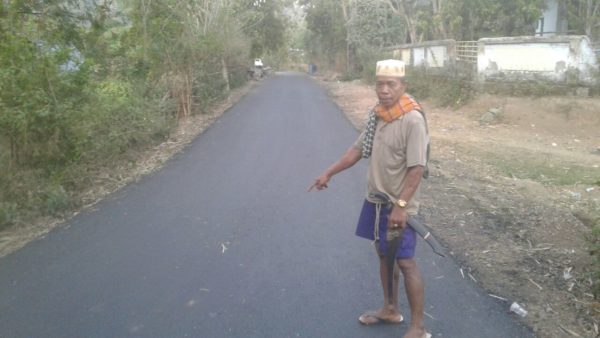 H. Arsyad Kahar, Warga Desa Woro, Kecamatan Madapangga saat menunjukkan jalan yang telah diaspal tuntas di persimpangan Desa Woro.